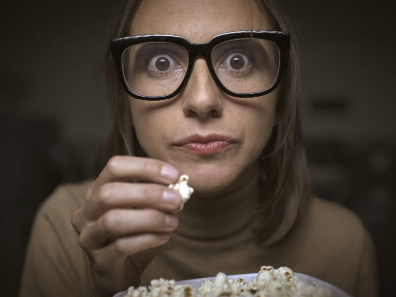 woman with glasses eating popcorn