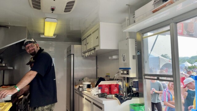 Gregory Foote, the manager of the Mobile Grace Cafe food truck, flashes a smile from his grill between cooking back-to-back orders of burgers, seared tuna and more for a long line of Maha festival-goers. Photo by Bridget Fogarty.