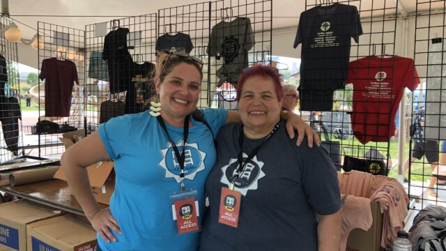 Longtime festival volunteers Erin Browning and Fritzi Schatz pose in the merchandise tent as they prepare for the growing evening crowds. Photo by Emma Schartz.