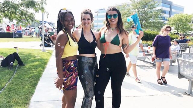 Sasha Quattlebaum, Maddie Rosonke, and Lauren Mankin smile, taking a break from roller skating around the festival grounds with bubbles and encouraging people to join the 1970s-themed dance parties at the Benson First Friday booth. Photo by Emma Schartz.