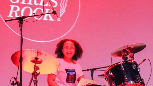 Camper Jasmine smiles behind her drum set at the Slowdown.
